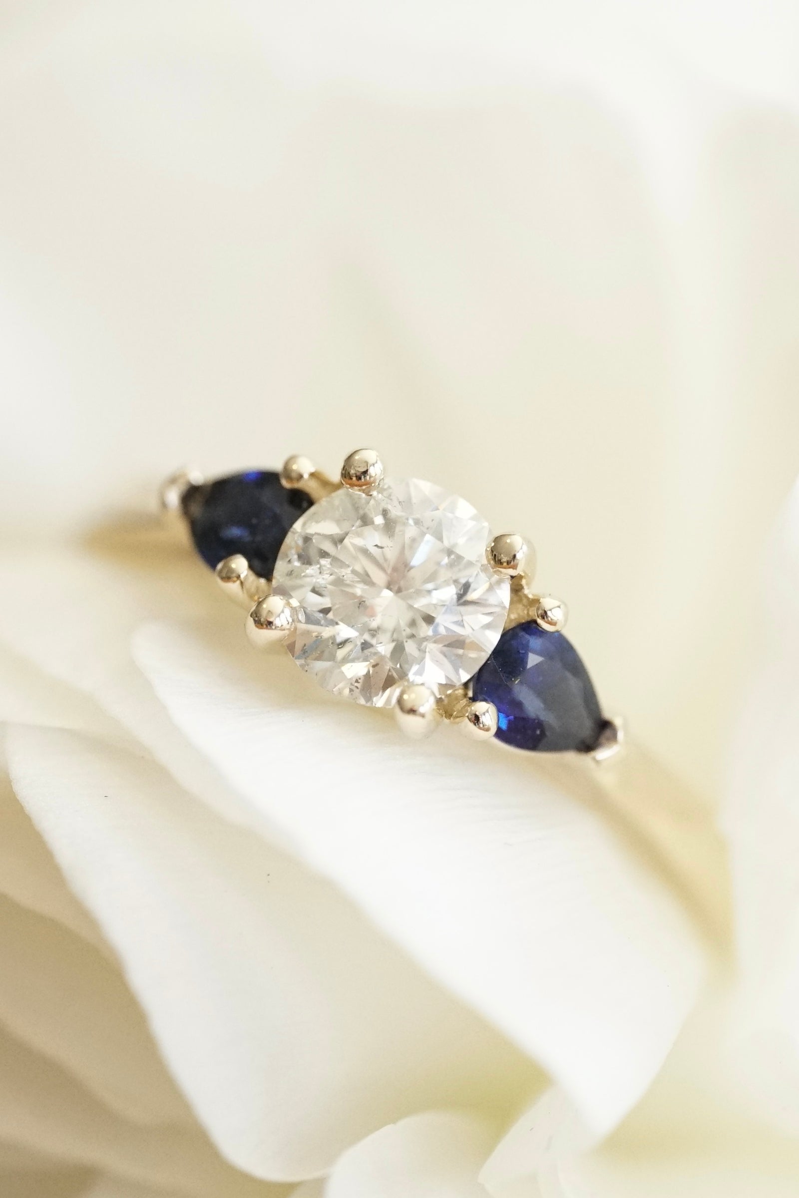 a yellow gold engagement ring with a diamond and blue sapphires