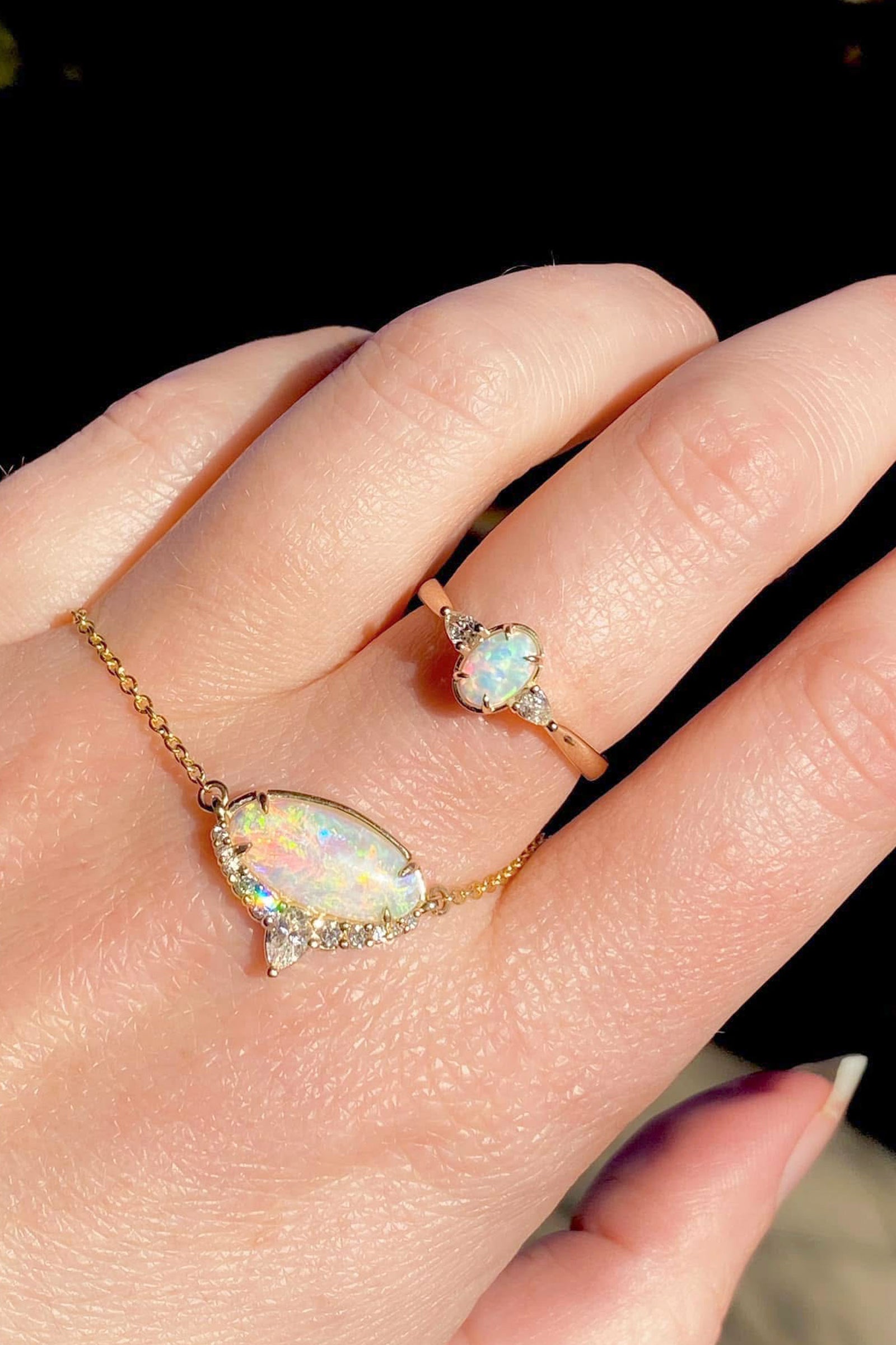 an opal ring and necklace set on a light skin tone hand