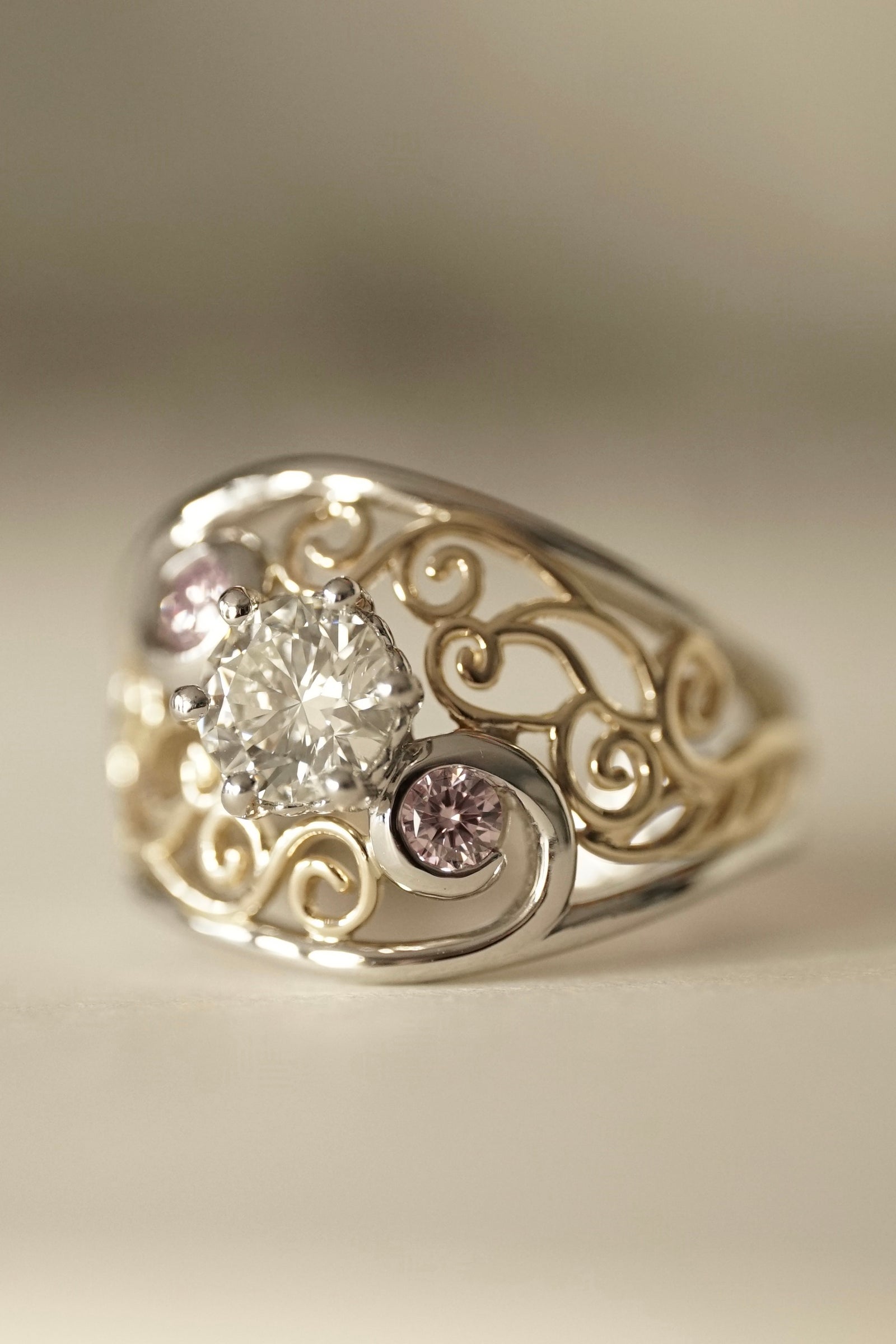 a yellow gold platinum pink and white diamond ring on a white groundplane