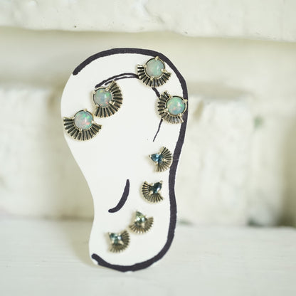 A hand drawn ear with 4 pairs of art deco inspired stud earrings, 2 pairs featuring opals and 2 pairs featuring pear shape sapphires