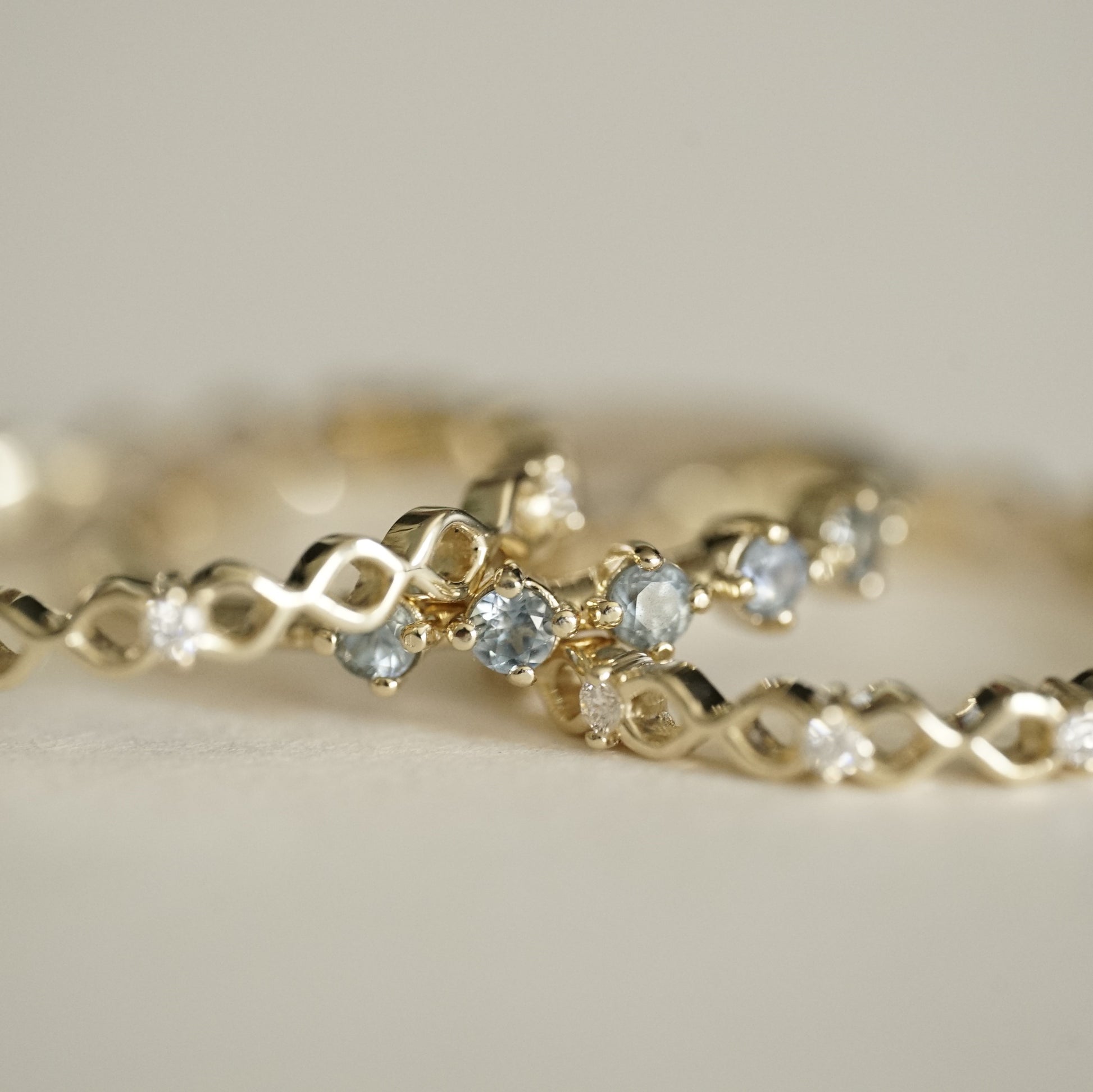 a ring with 5 prong set light blue sapphires between two open wirework yellow gold and diamond stacking bands