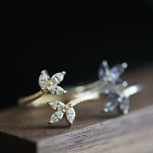 a macro photo of a yellow gold and diamond leaf inspired stacking ring on a wood grain display