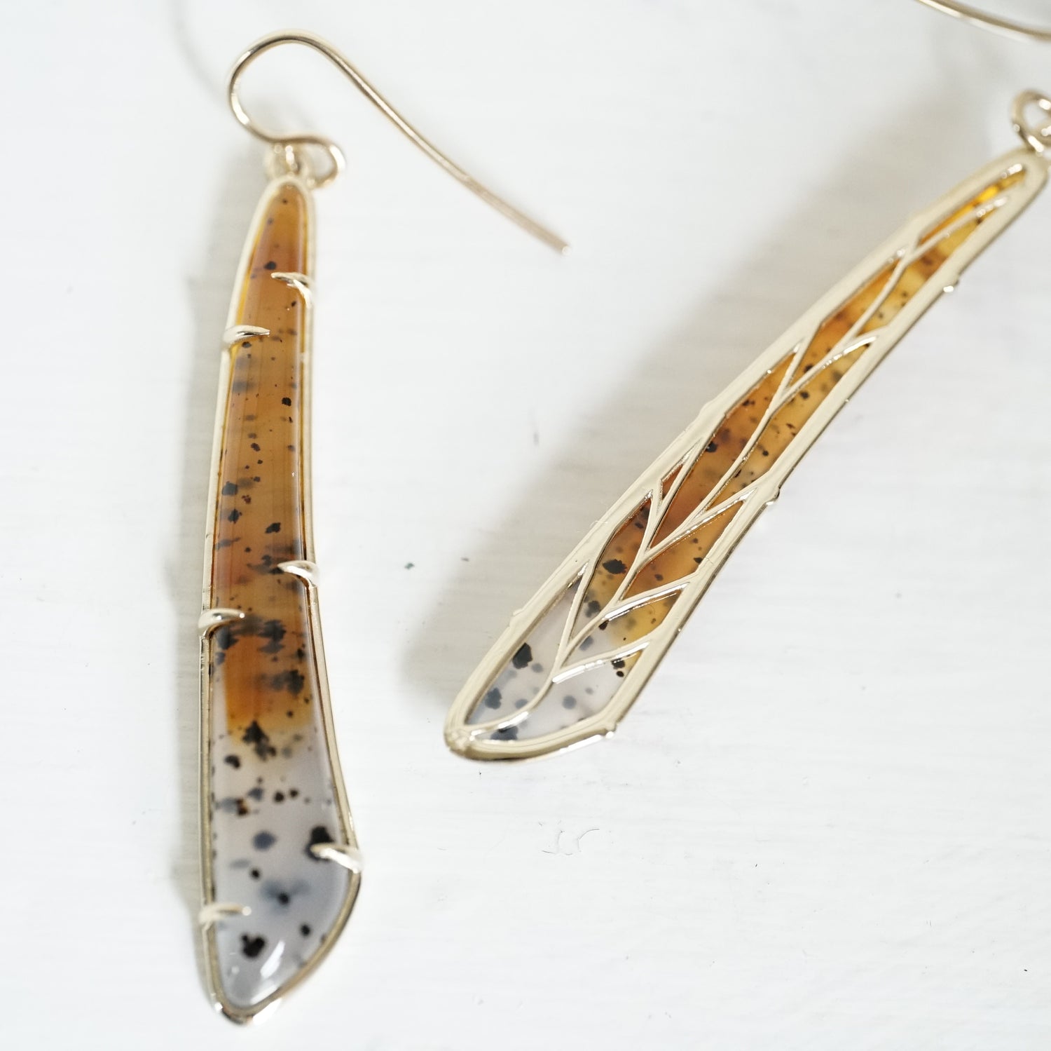 a pair of yellow gold earrings featuring elongated Montana agates which fade in color from yellow to clear and have natural black inclusions, one of the two rotated to show the leaf detail design on the backside