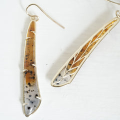 a pair of yellow gold earrings featuring elongated Montana agates which fade in color from yellow to clear and have natural black inclusions, one of the two rotated to show the leaf detail design on the backside