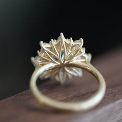 a yellow gold ring laying on a wood display is rotate 80 degrees to show the backside of the basket