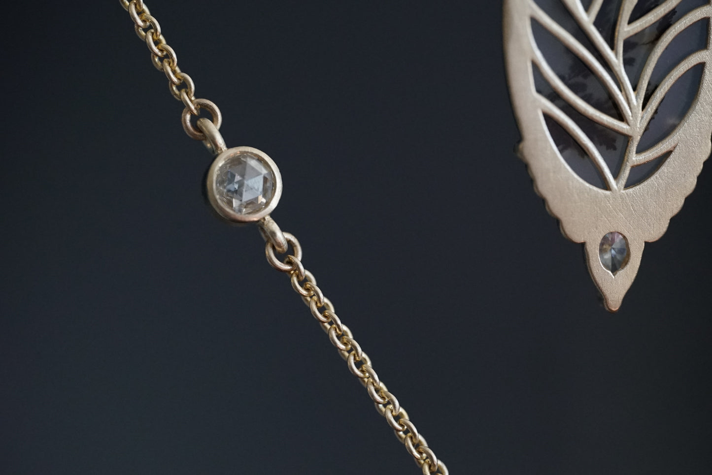 a macro photo of the backside of a yellow gold pendant and a close up of a bezel set rose cut diamond one a chain