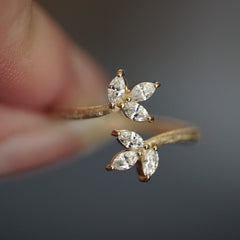 a macro photo of a yellow gold and diamond leaf inspired stacking ring held between fingers